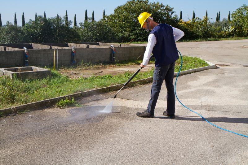 A man in a hard hat pressure washes a parking lot for a commercial building in Stewartstown, PA